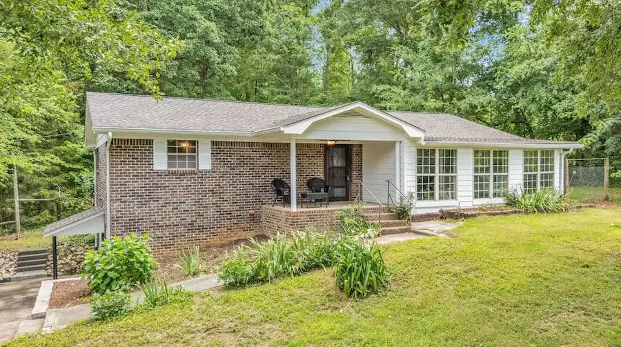 Before: brick home with overgrown plants along the front walkway and porch.