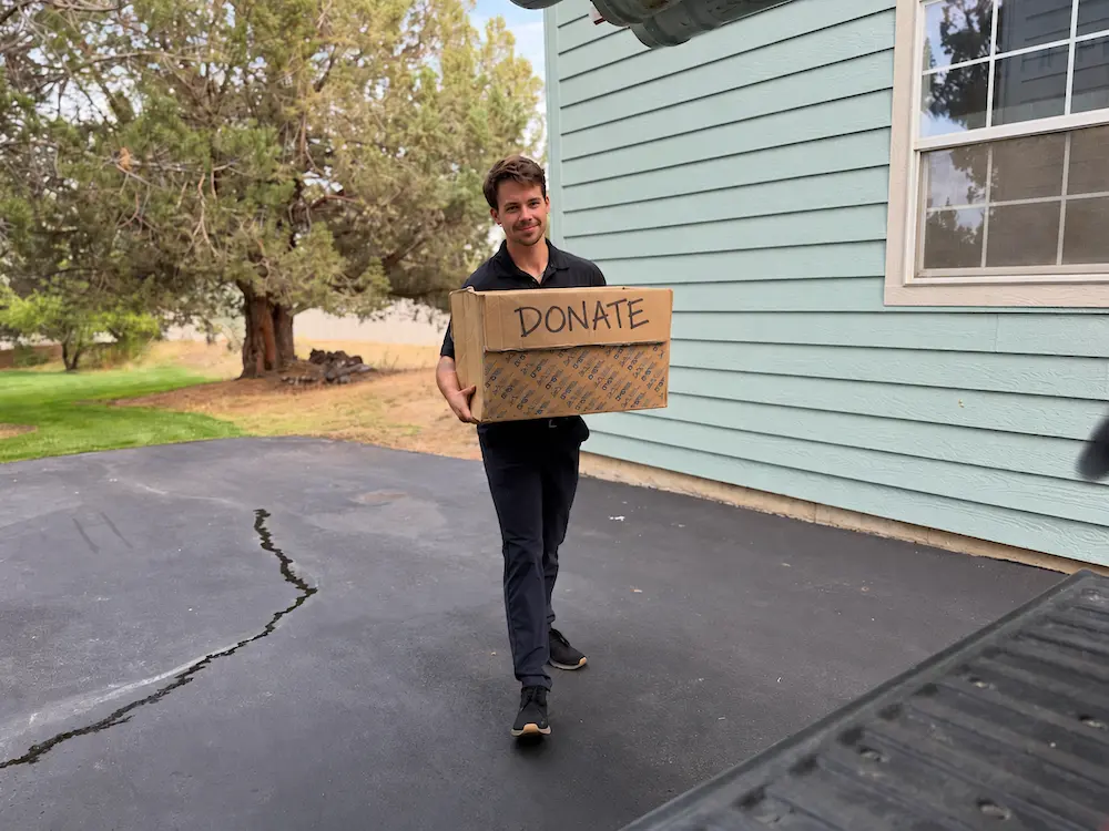 A Keep team member carrying a box labeled Donate out of a home.
